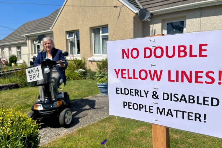 Karen Knight on her motability car outside her home with one of the signs she has made