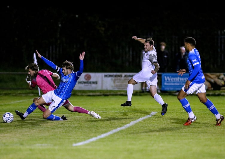 St Austell striker Liam Eddy wheels away in celebration as Buckland Athletic goalkeeper Adam Seedhouse-Evans and a defender look to clear his shot. Picture: Paul Williams