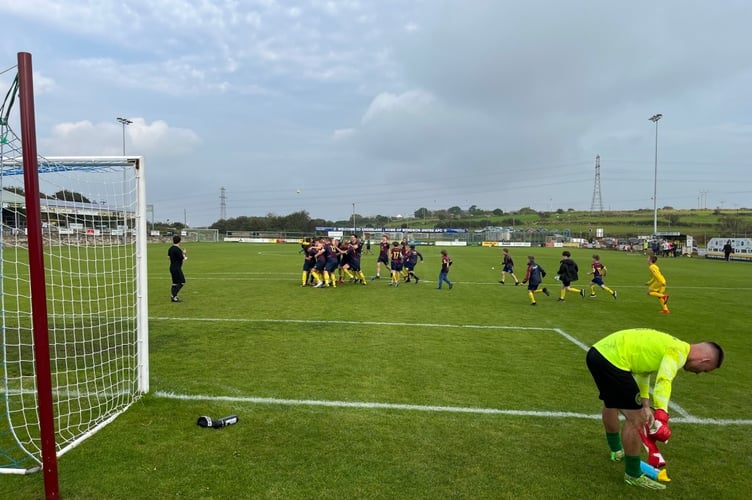 Wendron's players and mascots celebrate after Joe Souch's winning penalty as Blazey's Ryan Downing, who had to go in goal, due to Sam Borthwick's injury, picks up his stuff. Picture: Kevin Marriott