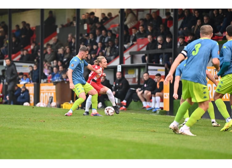 Truro's Will Dean (blue shirt) battles for the ball at Park View Road. Picture: Dave Budden