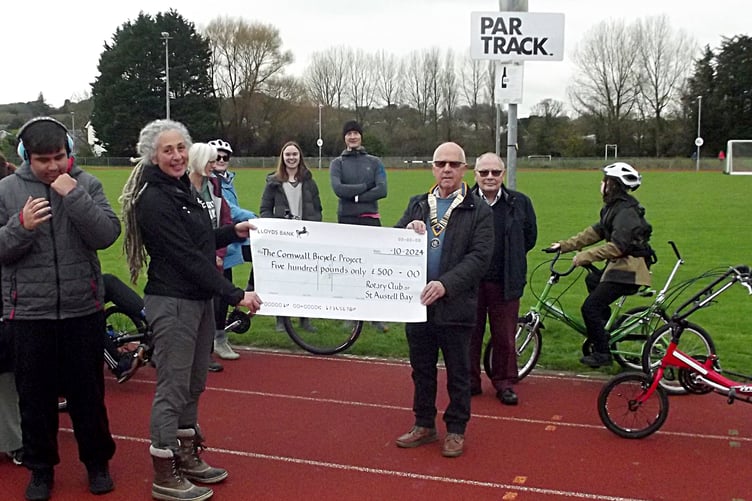 Rotary club president Paul Hancock presents a cheque to Emma Roberts of the Cornwall Bicycle Project at the Par Track.