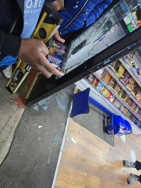 The broken shop window at Muthu's Mini Market in Saltash