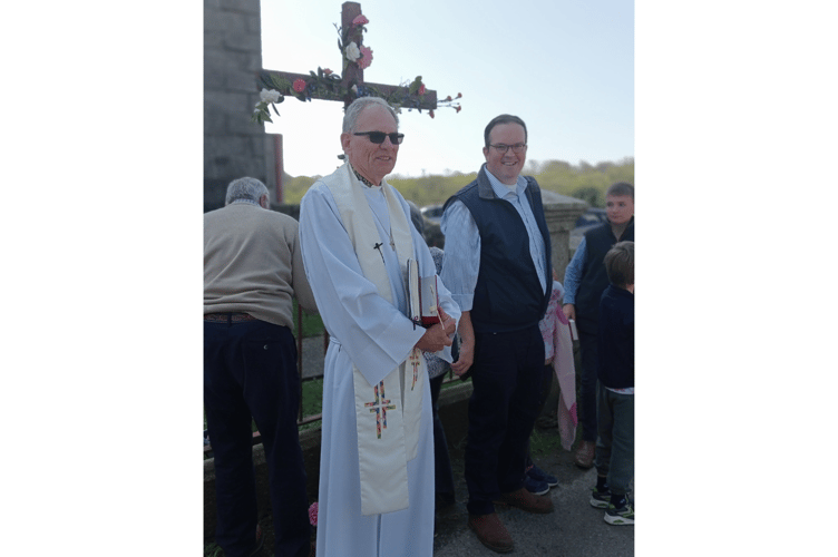 Floral tributes being attached to a wooden cross.  Photo by Sandra Roberts.