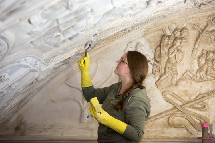 A conservator using a brush to wash the Long Gallery ceiling at National Trust Lanhydrock, Cornwall, showing clean and dirty areas of the ceiling (C)National Trust Images_Faye Rason
