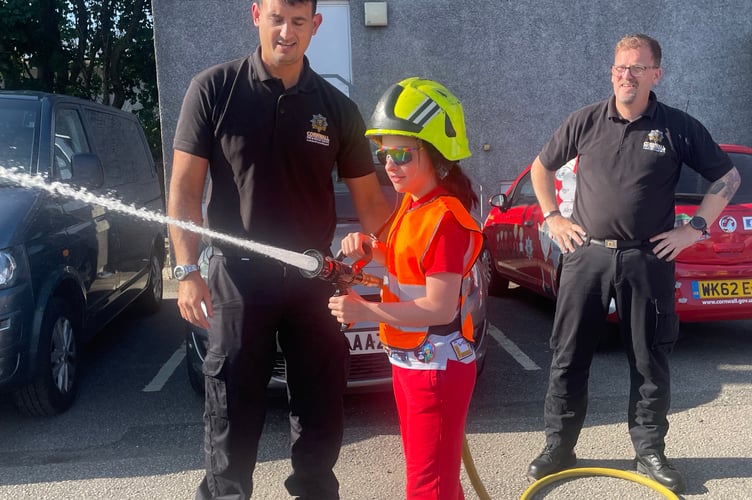 These young member of the 1st Liskeard Rainbows tries her hand at working the hose with Liskeard Community firefighters