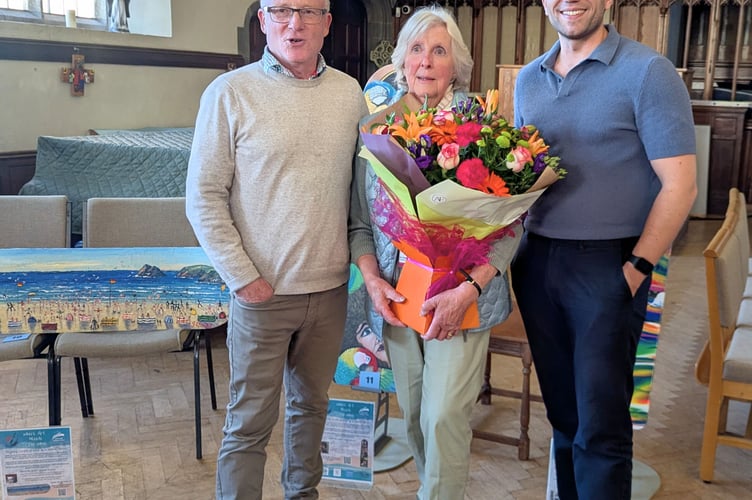 Sue Dennett (pictured centre with Ben Statham-Wilkins (right) and Alistair Whyte (left) of Cornwall Hospice Care) being presented with a bunch of flowers at St Michael's Church for her fundraising efforts