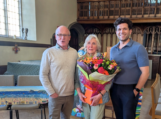 Sue Dennett (pictured centre with Ben Statham-Wilkins (right) and Alistair Whyte (left) of Cornwall Hospice Care) being presented with a bunch of flowers at St Michael's Church for her fundraising efforts