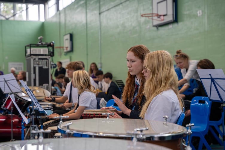 The super orchestra consisted of musicians playing various instruments including drums, guitar, percussion, strings, woodwind, brass, saxophone and keyboards