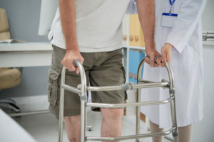 Man making first steps with help of walker after rehabilitation therapy