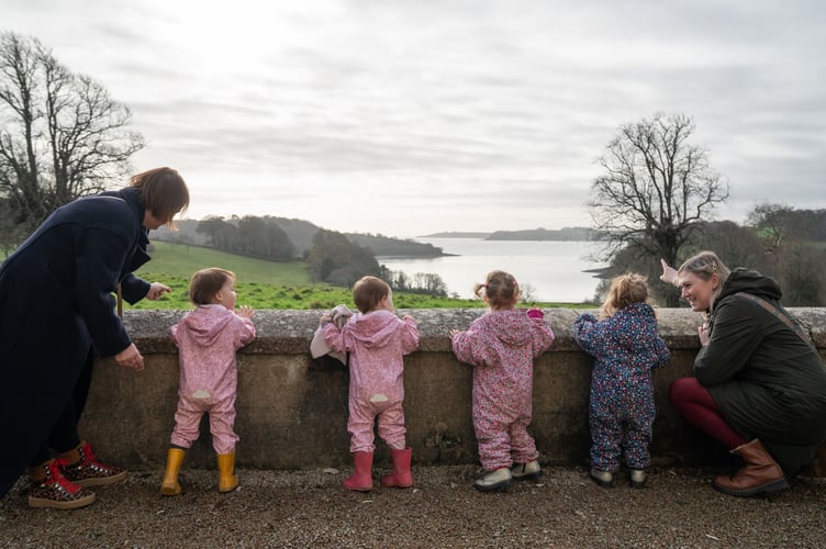 Visitors with young children look out towards the River Fal from the Terrace at Trelissick, Cornwall