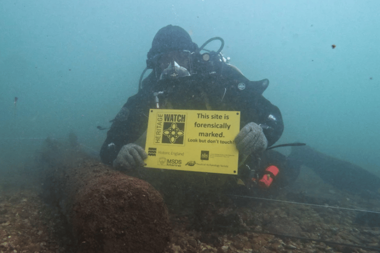 A diver holding an underwater sign indicating that a site has been forensically marked. This means visiting divers can look but not touch. (Picture: MSDS Marine) 