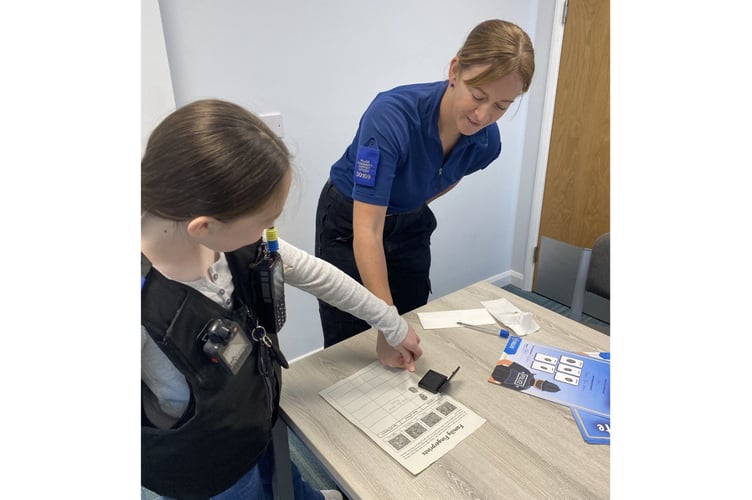 A young pupil from Carbeile Junior School gets to take the fingerprints of PCSO Bex Steed