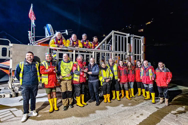Looe Valley Rotary Club past president David Bunt and treasurer Paul Roach hand over the three torches to the volunteer crew members of Looe RNLI