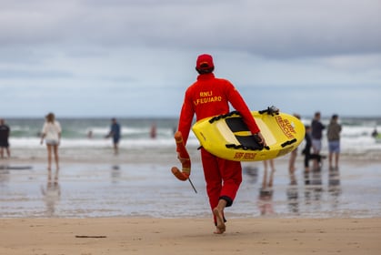 RNLI lifeguard carrying a rescue board into the sea at Perranporth beach (Picture: RNLI-Lee Hawkins)