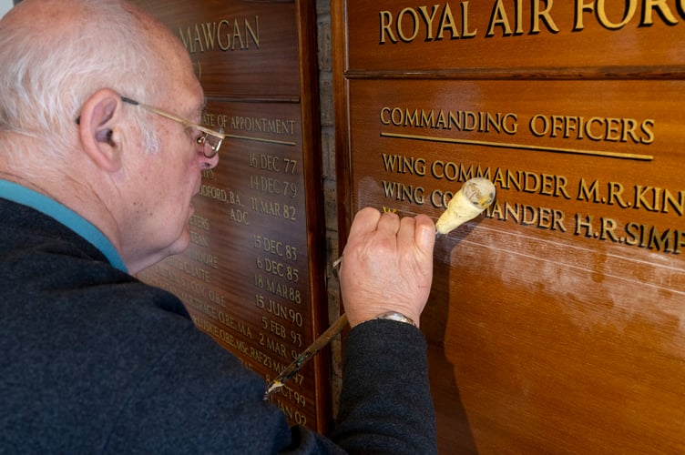 Images of  the David Dunkley, Director of Parc Signs, hand painting the name of incoming Station Commander, Wing Commander Gareth Elliot, onto the command board. Mr Dunkley has personally added the name of every Station Commander to the board since 1982. 