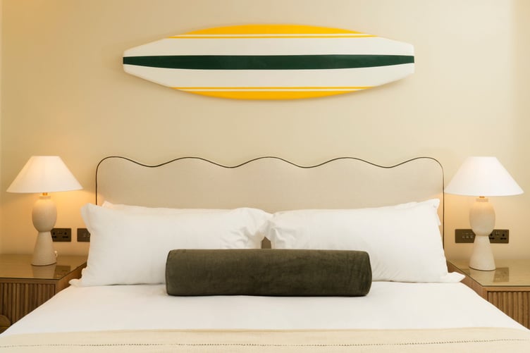 A surfboard adorns a wall in a refurbished bedroom